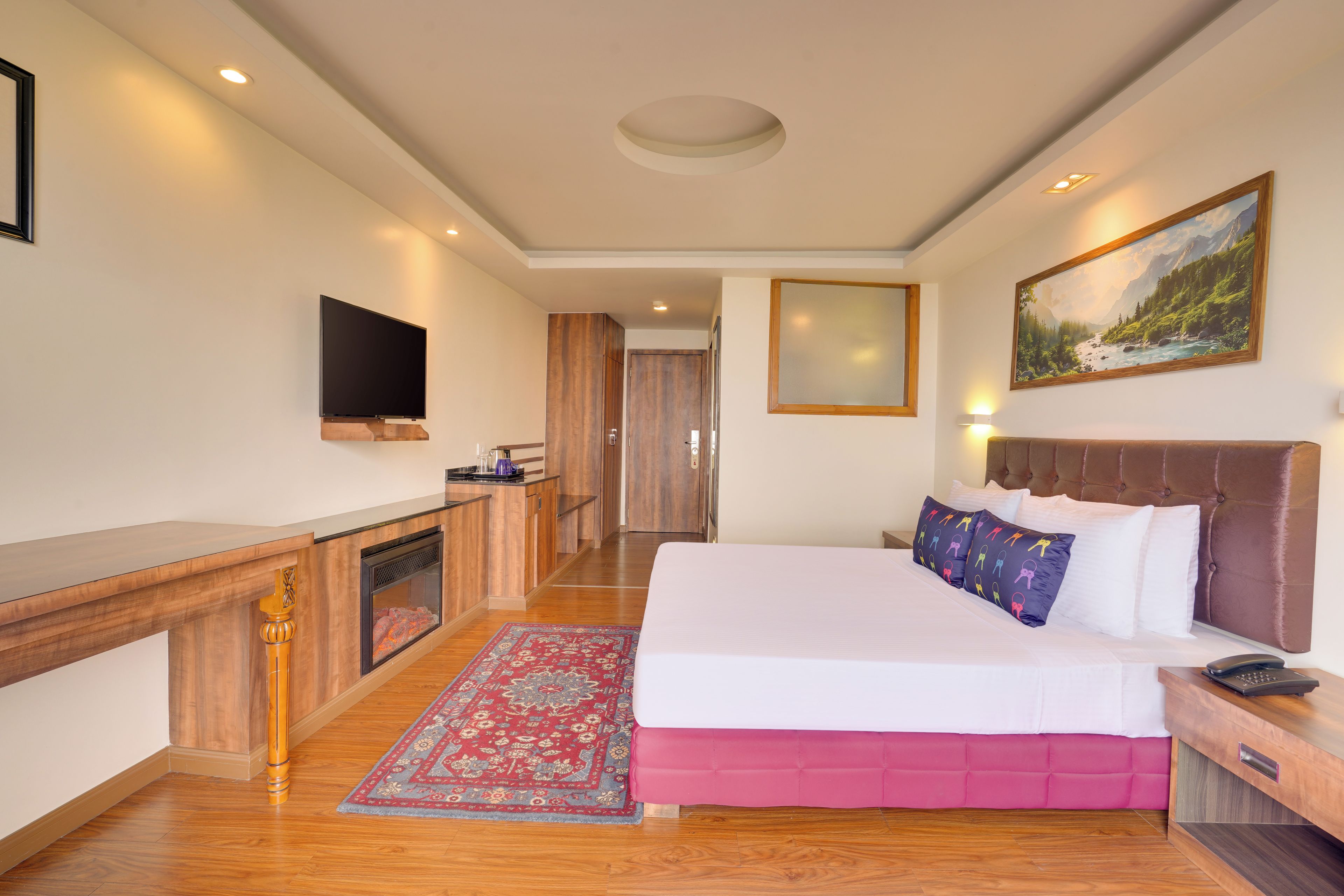 A hotel room with a bed, bedside table, TV, artwork, and a view of the hallway.