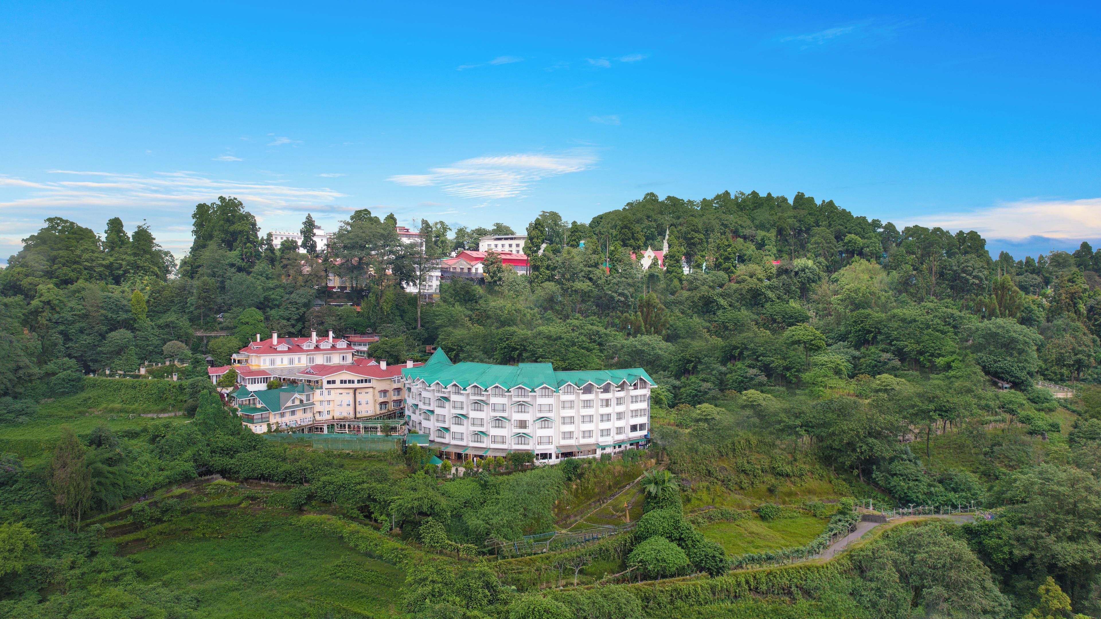 Un hotel con varias edificaciones, rodeado de abundante vegetación y colinas.