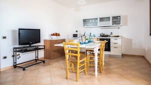 Eine kleine Küche mit Essbereich, einem Fernseher auf einem Schrank und Schränken oberhalb der Arbeitsplatte.