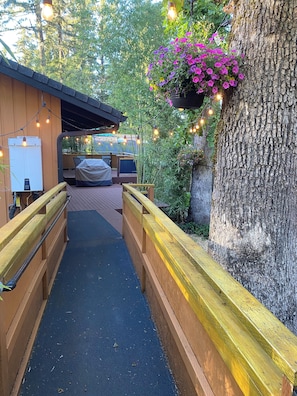 A wooden deck with a covered seating area, a hanging flower basket, and string lights.