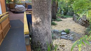 A wooden deck with outdoor seating, a large tree, and a hanging flower basket.