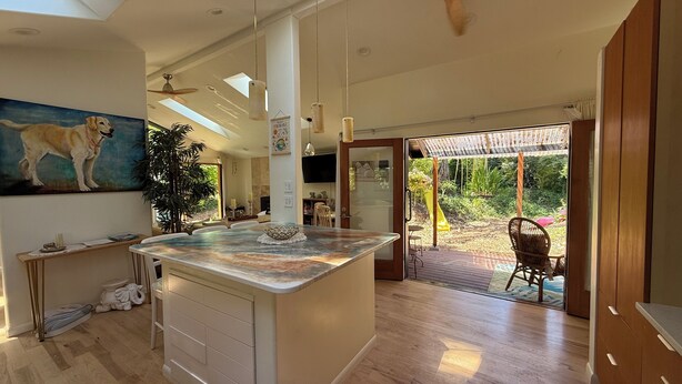 A spacious living area with a large island, a ceiling fan, and a view of the outdoors.