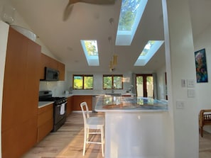 A modern kitchen with skylights, wooden cabinets, and a central island.