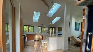 A spacious kitchen with a central island, wooden flooring, and skylights.