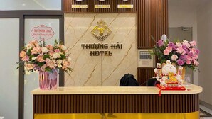 A hotel reception desk with a ceiling fan, clocks, and floral arrangements. - Thuong Hai Hotel - by Bay Luxury (Hanoi)