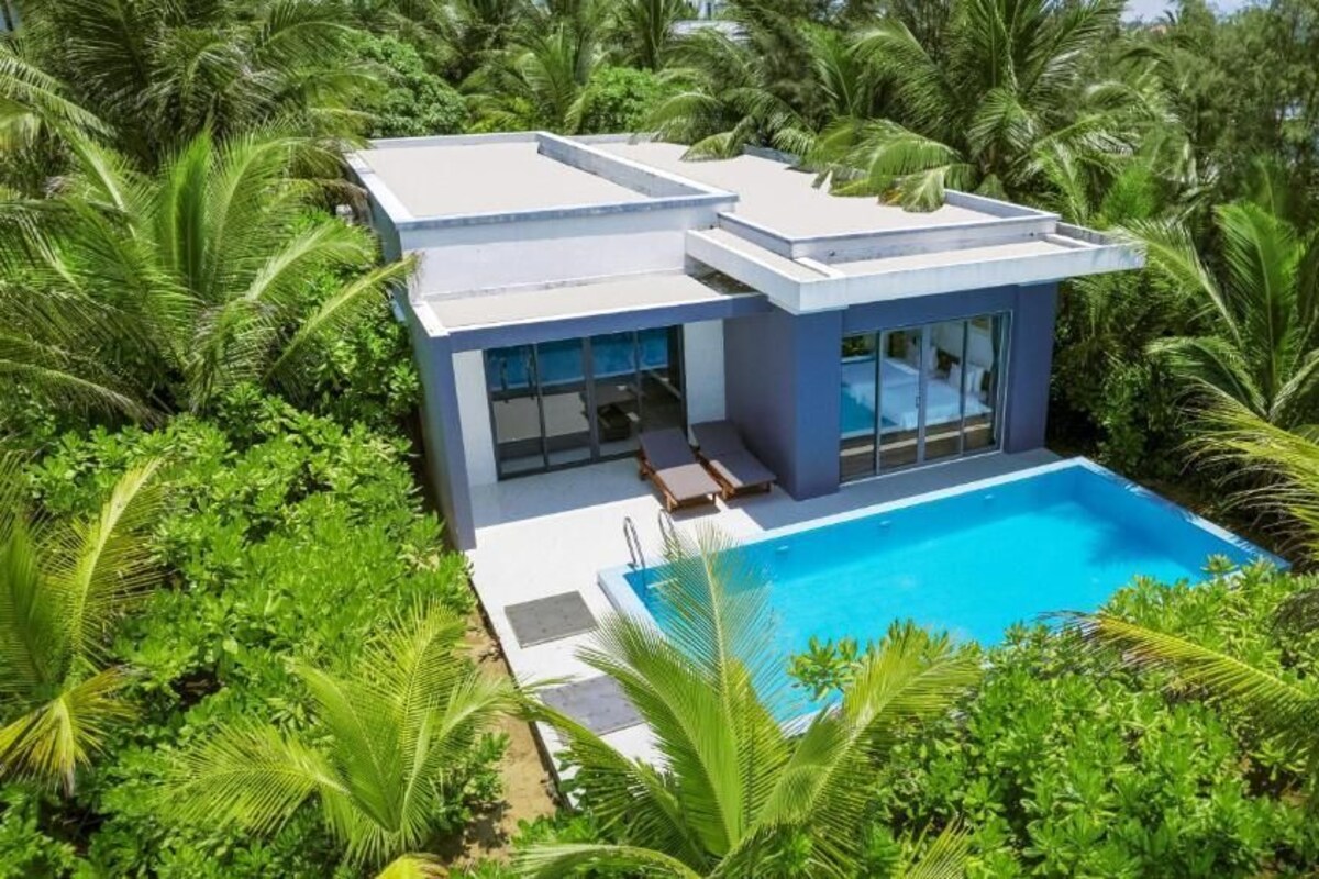 Ett modernt hus med en swimmingpool, omgivet av frodig grönska.