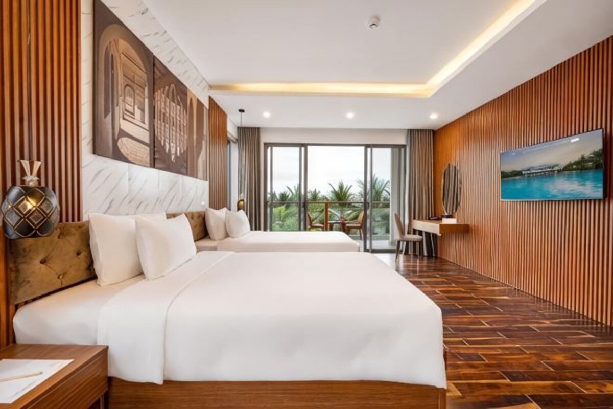 Une chambre d’hôtel avec deux lits, une grande fenêtre, un tableau et un plancher en bois.
