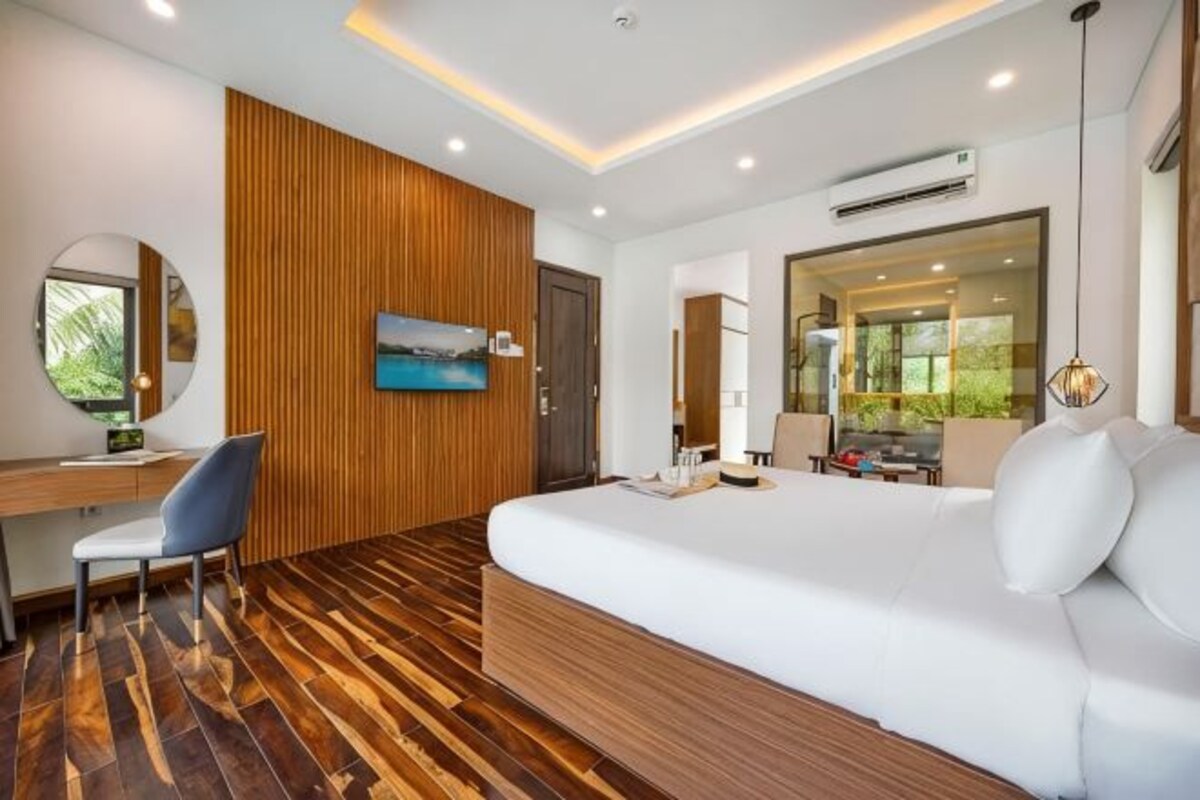 Une chambre à coucher moderne avec un plancher en bois, un grand lit, un bureau, une chaise et un téléviseur.