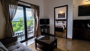Una habitación de hotel moderna con un gran ventanal corredero que da a un balcón, una cama con cabecera, un televisor de pantalla plana y una cafetera.
