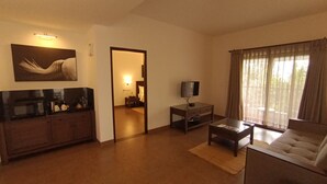 Una sala de estar con un sofá, una mesa de centro, un televisor sobre un mueble, un cuadro en la pared y un espejo que refleja la habitación.