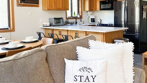Eine moderne Küche mit Holzausstattung, Edelstahlgeräten und einer Essecke mit einer Couch und Kissen.