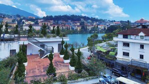 A coastal cityscape with a river, buildings, and a mountain in the background. - Sapa Crown Hotel (Sa Pa)