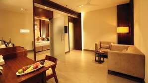 A modern hotel room with a dining area, a sofa, and a ceiling fan. - Magnet Hotel (Kannur)