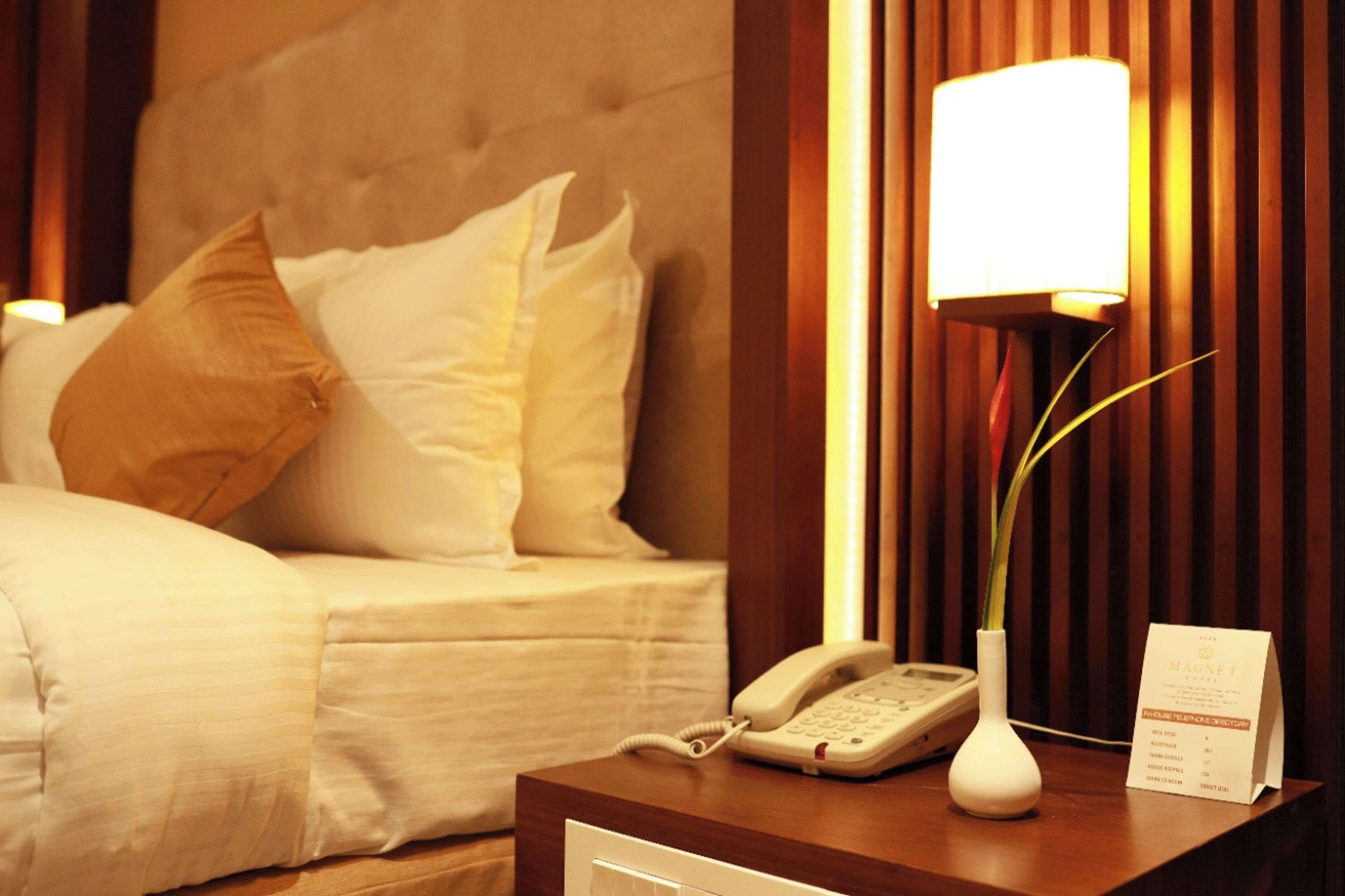 Een hotelkamer met een bed, een telefoon, een lamp en een menuhouder.