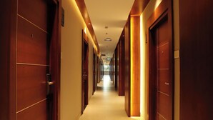 A hotel corridor with wooden doors and recessed lighting. - Magnet Hotel (Kannur)
