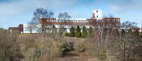 A large hotel with multiple buildings, surrounded by trees and a grassy area.