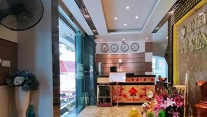 A hotel lobby with a reception desk, a clock, and a decorative wall.