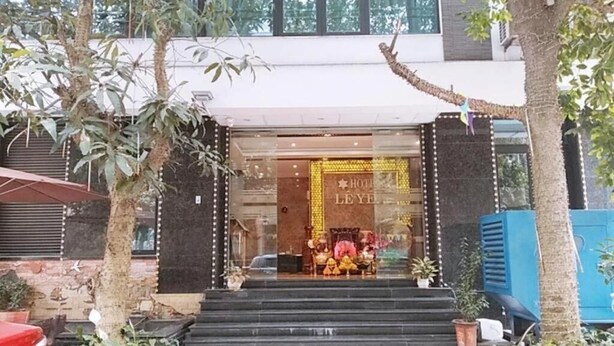 A hotel entrance with a glass facade, steps leading up to the entrance, and potted plants around.