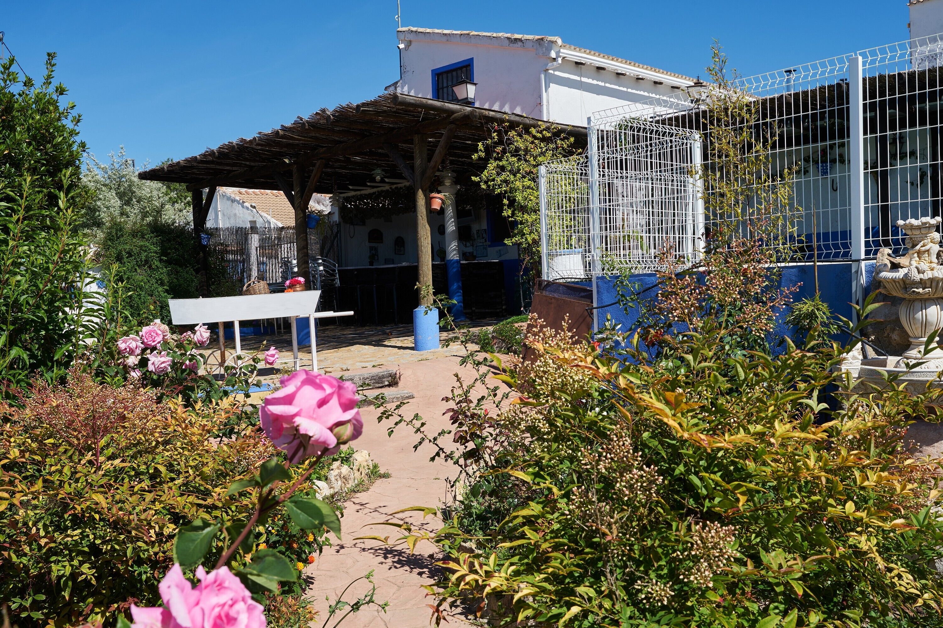 Un jardin agrémenté d’une pergola, d’une clôture blanche et d’une statue.