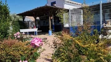 Un jardin agrémenté d’une pergola, d’une clôture blanche et d’une statue.