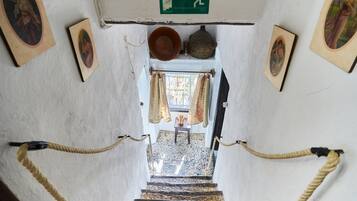 Una escalera con barandilla de cuerda, un letrero de salida de emergencia verde y cuadros en las paredes.