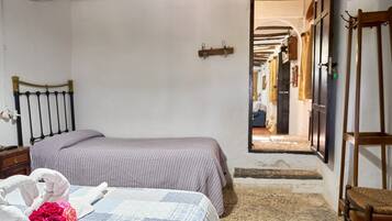 A bedroom with a bed, a nightstand, a chair, and a doorway leading to a corridor.