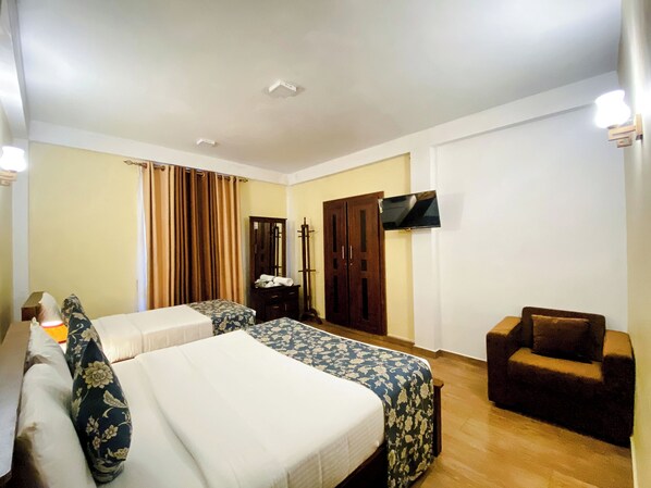 A hotel room with two beds, a TV, a wardrobe, and a chair. - Summer Glow Guest - Nuwara Eliya (Nuwara Eliya)
