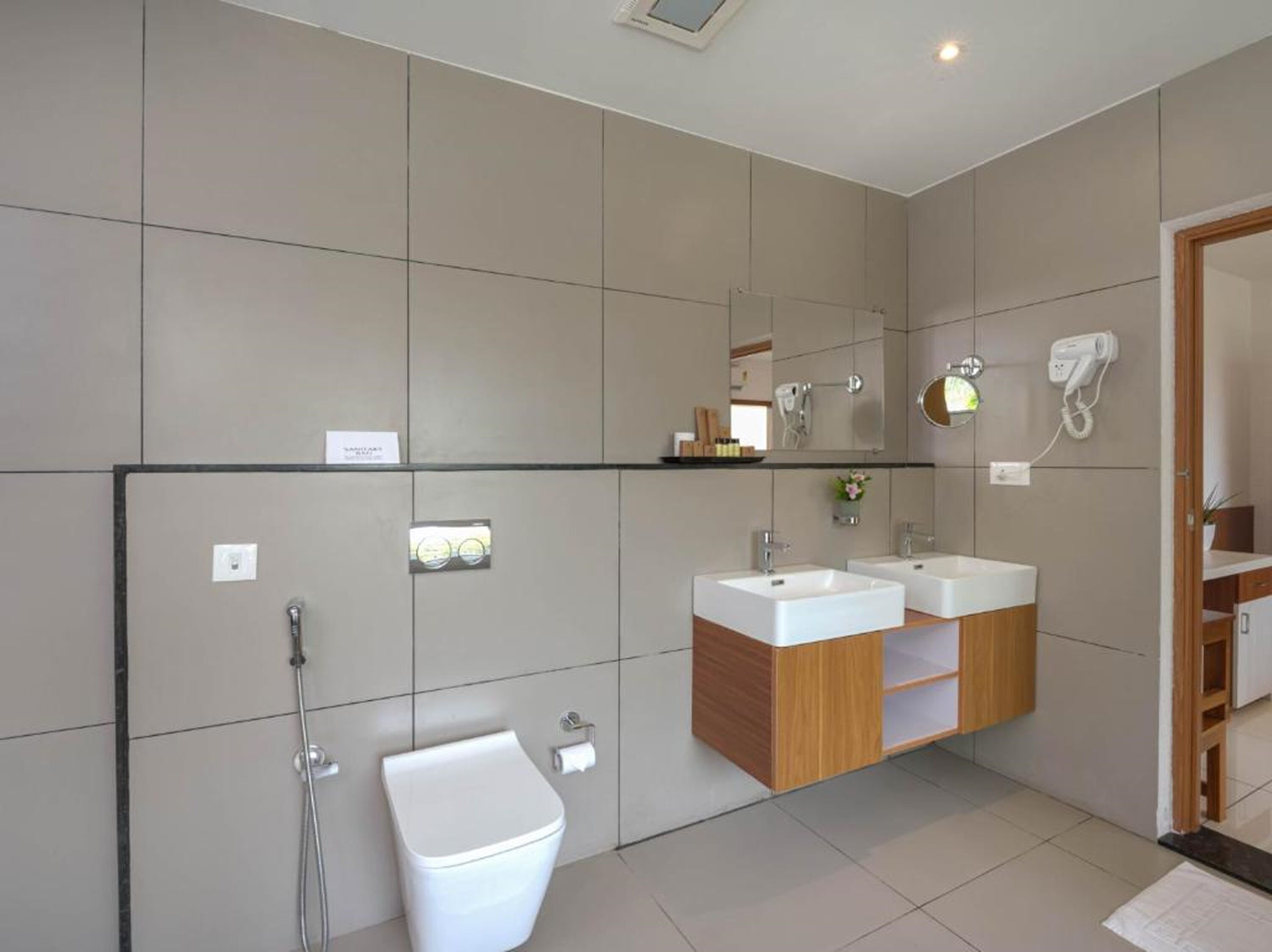 A modern bathroom with two sinks, a toilet, and a shower.