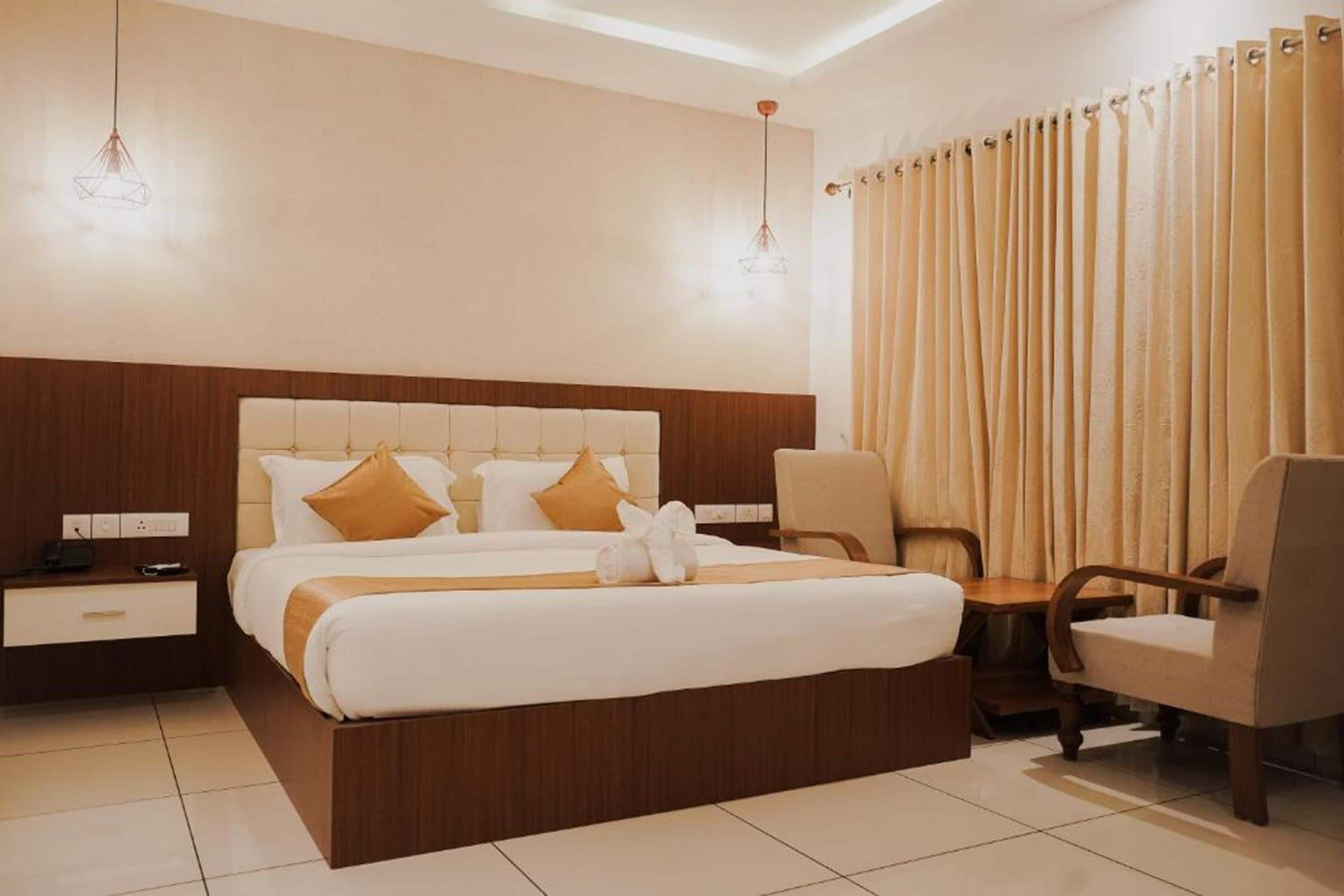 A hotel room with a large bed, a wooden headboard, a bedside table, a chair, and a window with curtains.
