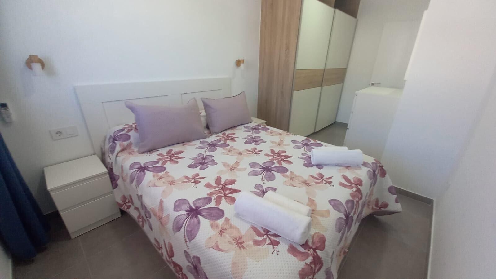 Un dormitorio con cama, mesita de noche, armario y baño.