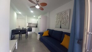 A modern living room with a blue sofa and a dining area with a table and chairs.