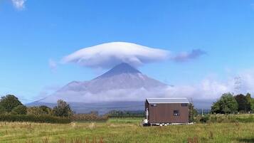 A single-story building with a flat roof, situated in a grassy field with a mountain in the background.