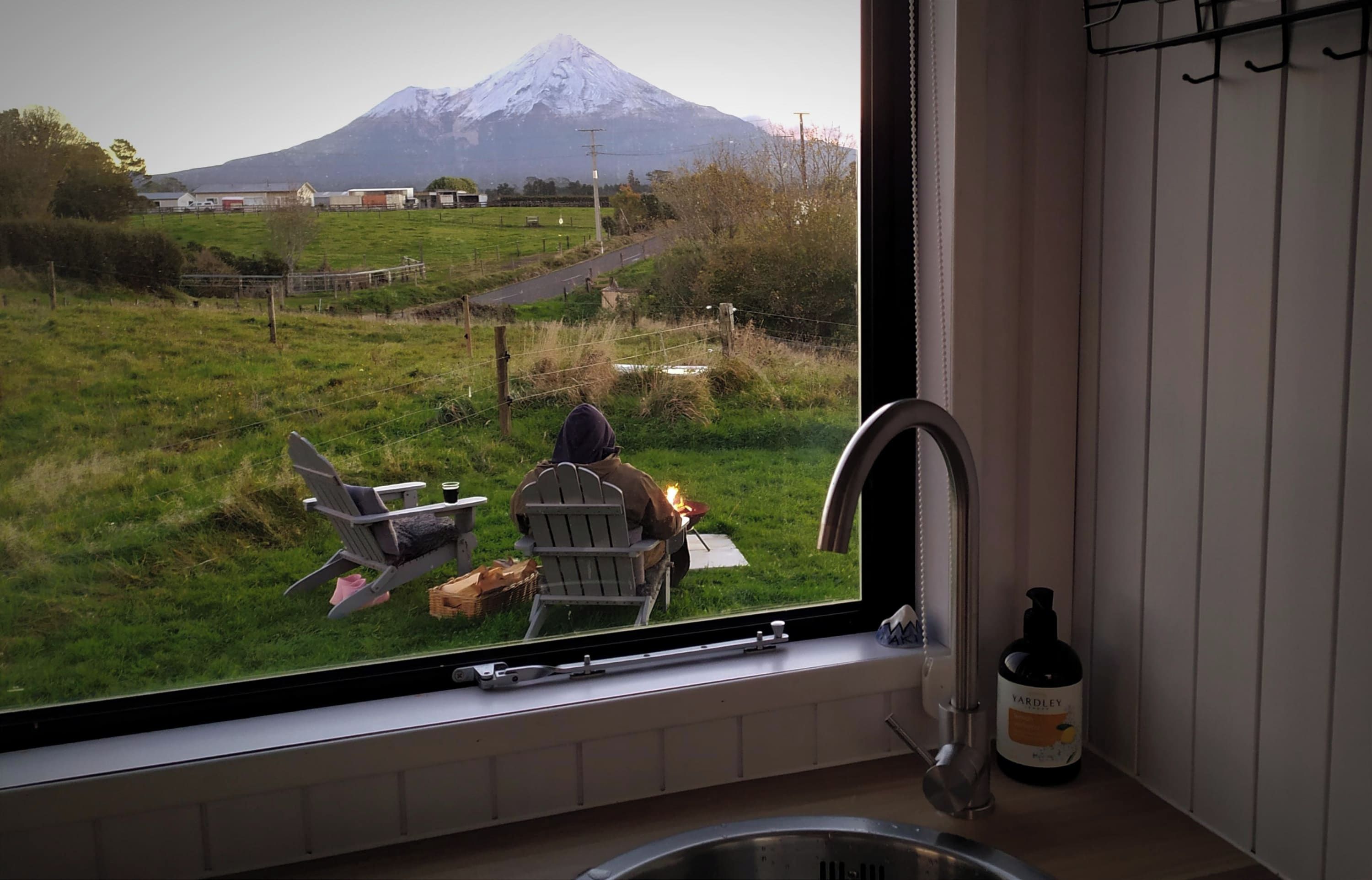 Una ventana con vista a un campo cubierto de hierba y una montaña.