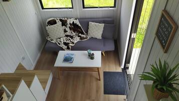 A room with a sofa, a coffee table, a book, and a plant.