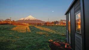 A view of a grassy field with a mountain in the background. - Taranaki Creekside TUI by Tiny Away (Midhirst)