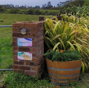 A brick wall with two signs, one labeled "Taramaki TUJ" and the other "Taramaki KEA". - Taranaki Creekside TUI by Tiny Away (Midhirst)