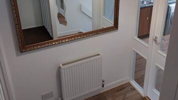 A room with a large ornate mirror, a white radiator, and a wooden floor.