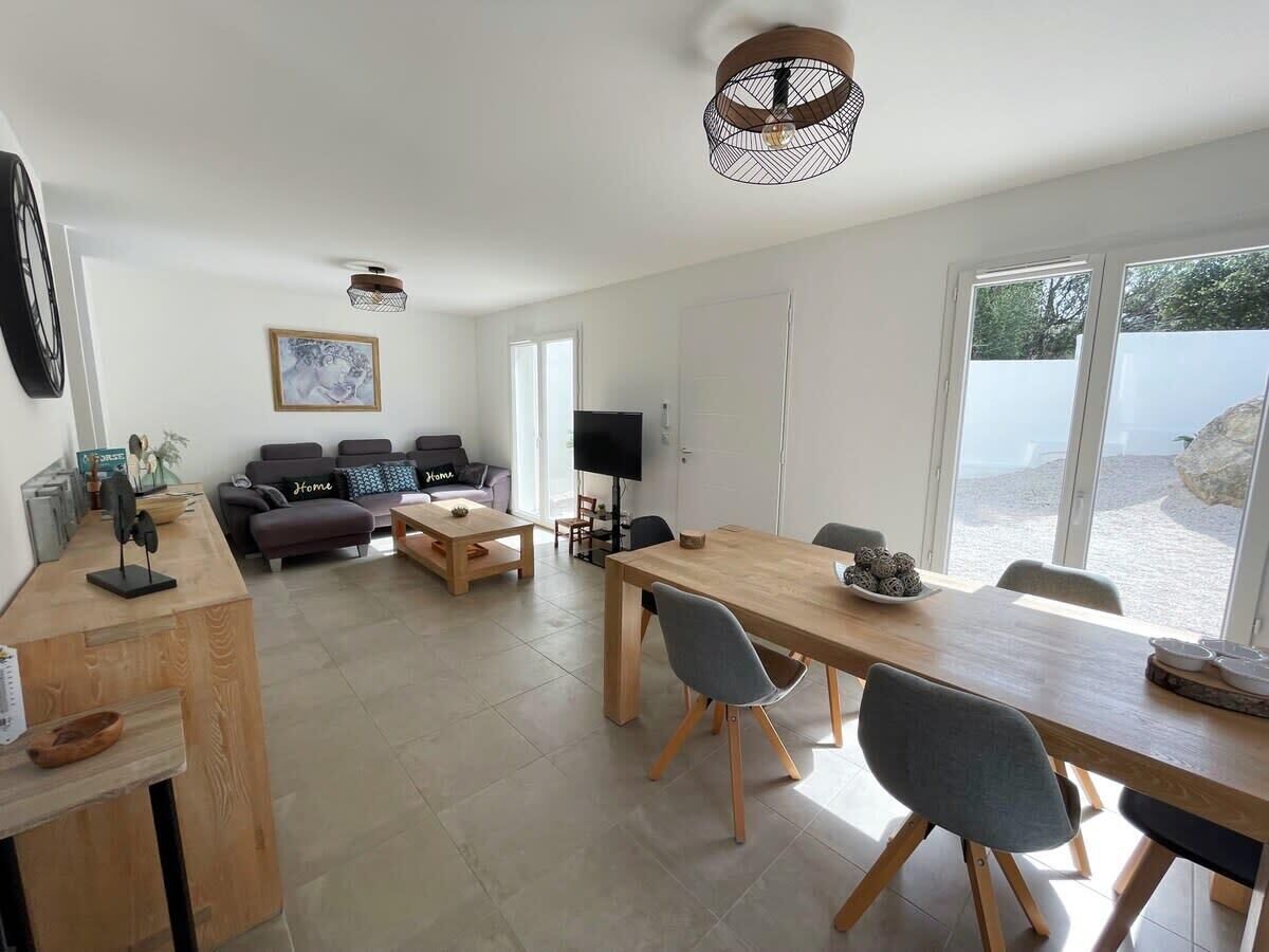 Un salon moderne avec un canapé, une table basse et une table à manger. On y trouve également un téléviseur et une fenêtre donnant sur un beau paysage.