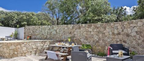 An outdoor patio area with stone walls, wicker furniture, and a table set for dining.