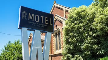 A motel sign with a crown logo, indicating a possible royal affiliation, and a contact number.