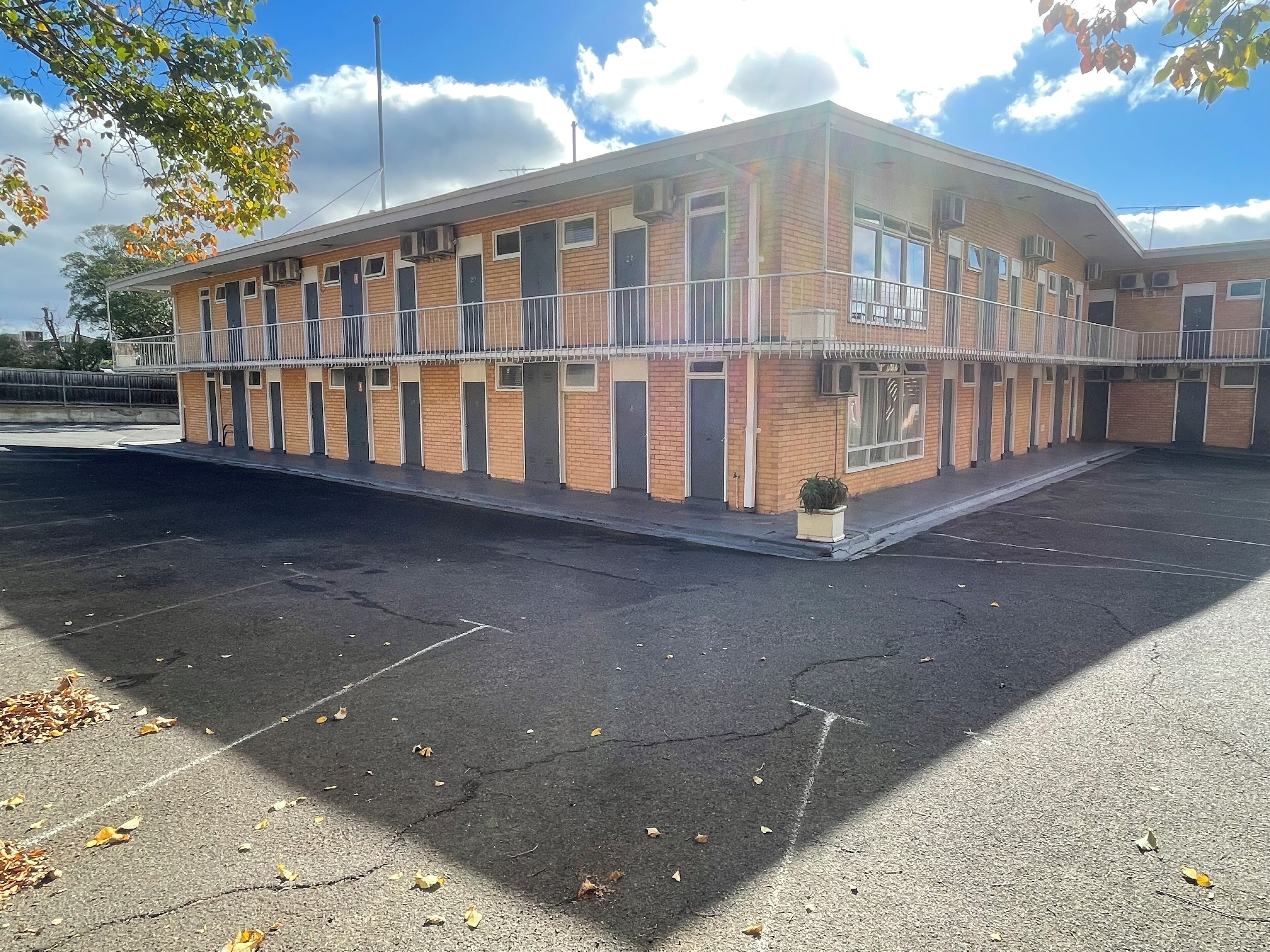 A multi-story building with a brick facade, multiple windows, and a flat roof.