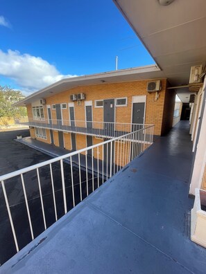 A building with a brick facade, multiple doors, and a covered walkway with a railing. - Kingsway Motel Geelong (Newtown)