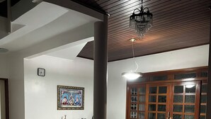 A spacious dining area with a tiled floor, a dining table with chairs, a wooden cabinet, and a wall-mounted clock. - Casa Ampla com 4 Suítes com Escritório, Aceita Animais de Estimação (São Pedro Teresina)