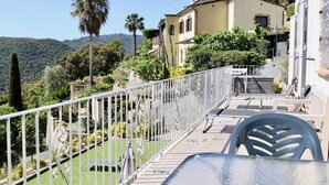 A terrace with a view of a hillside, a pool, and a building with a balcony. - House with garden and private pool 6km beach (Calonge)