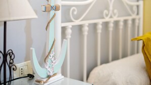 Un letto con testiera bianca, un oggetto decorativo bianco e verde acqua sul comodino, una lampada e un panno giallo.