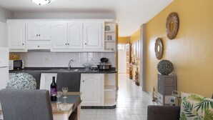 Una cucina moderna con mobili bianchi, un piano di lavoro nero e un'area pranzo con tavolo e sedie.