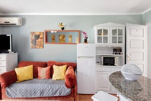 Un espacio habitable compacto con sofá, microondas, refrigerador y encimera de cocina.