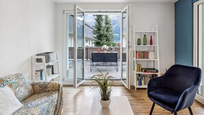 A living room with a sofa, a coffee table with a plant, a bookshelf, and a chair. - BeKb-Gebäude Apt. 01 by Interhome (Wengen)
