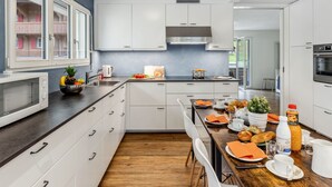 A modern kitchen with white cabinets, a wooden countertop, and a dining area set for breakfast. - BeKb-Gebäude Apt. 01 by Interhome (Wengen)
