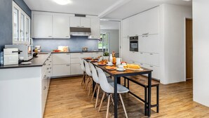 A modern kitchen with white cabinets, a wooden dining table, and a built-in oven. - BeKb-Gebäude Apt. 01 by Interhome (Wengen)